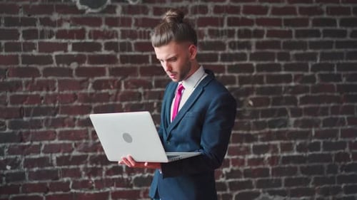 Man Standing Indoor Using Laptop Dressed Suit Red Brick Wall Background
