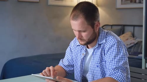 Young Adult Uses Tablet in Bedroom