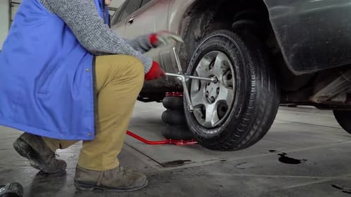 Worker unscrew the wheel from the car