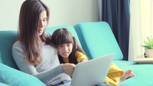 Woman and Child Looking at Laptop on Couch