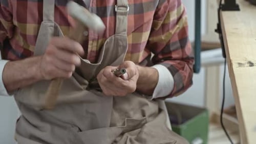 Jeweler Shapes Metal Piece With Hammer at Work Table