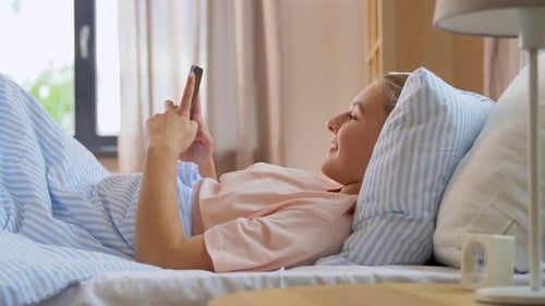Woman Relaxing in Bed Using Smartphone