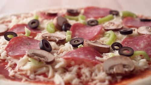 Die Kamera folgt dem Legen von geschnittenen schwarzen Oliven auf einen Pizzateig. Zeitlupe.
