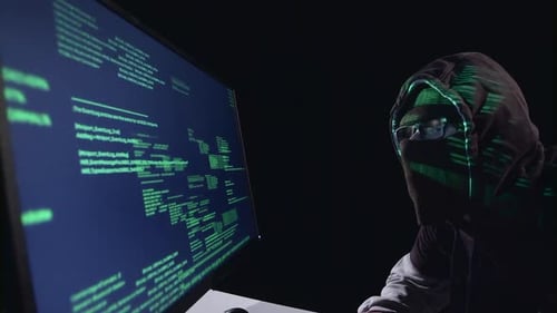 Spy Hacking Computer Sitting in a Dark Room. Black Background