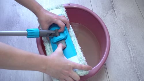 The Man Removes the Rag From the Mop and Rinses It in a Basin of Water Then Squeezes Out the Rag