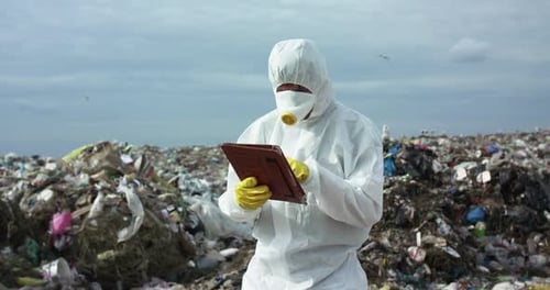 Worker in Hazmat Suit Analyzing Landfill Data