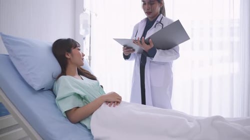 A female patient lies on a hospital bed while listening to the results of the surgery.