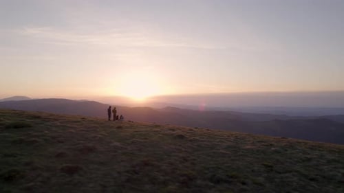 Flying Over the Silhouettes of Hikers Watching the Sunset at the Top of the Mountain While Taking a