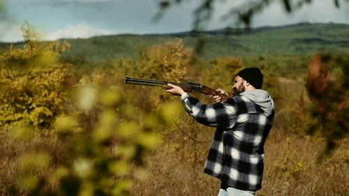 Bearded Man Aims Rifle in Rural Field