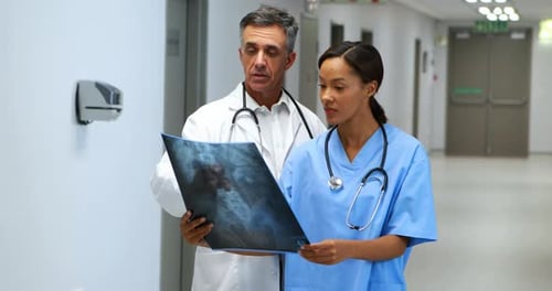 Medical Professionals Examining X-ray in Hospital Hallway