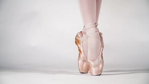 Beautiful Legs of a Ballerina in Pointe on a White Background Closeup