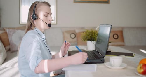 Woman with Headset Working on Laptop at Home