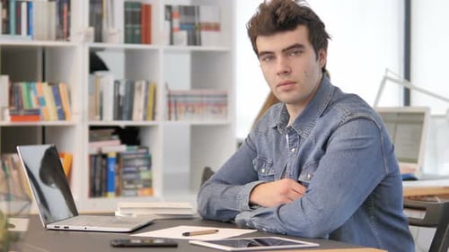 Young Adult Sits at Desk with Laptop and Tablet