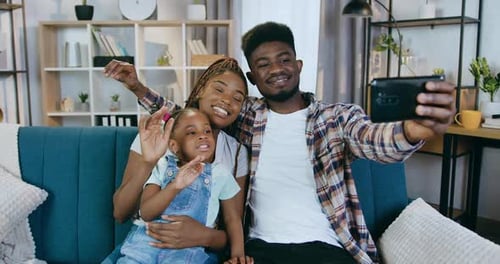 Padres sonrientes con hija que usan un teléfono inteligente