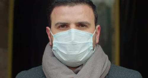 Close Up Portrait of Handsome Male in Medical Mask Standing Outdoors on Street and Looking at Camera