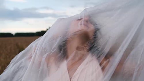 Woman Inside Plastic Sheet in Wheat Field