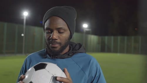 Man with Soccer Ball on Sports Field at Night