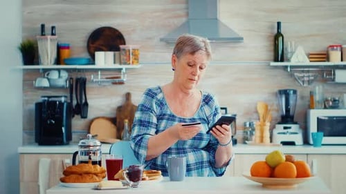 Woman Uses Phone and Credit Card in Kitchen