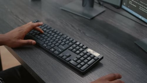 Nahaufnahme von Händen afroamerikanischer Programmierer, die beim Betrachten des Computers Code auf der Tastatur eingeben