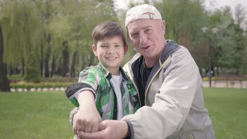 Child and Senior Smiling and Waving in Park