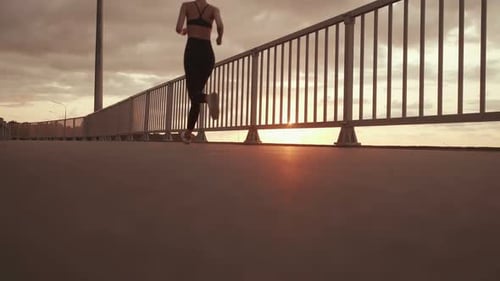 Young Woman Runs Across Bridge at Sunset