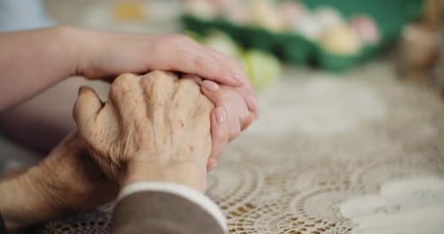 Frau berührt die Hände eines älteren Mannes und unterstützt älteren Mann