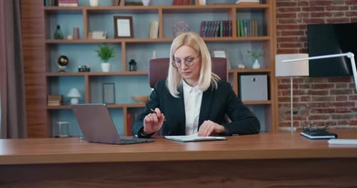 Businesswoman Working with Information on Laptop and Business Reports in Modern Office