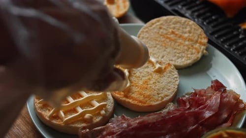 Creamy Sauce Being Added To Burger Buns