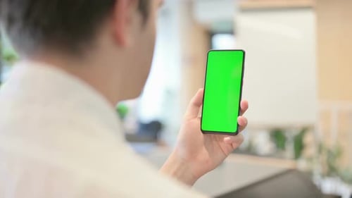 Young Man Using Smartphone with Green Chroma Screen