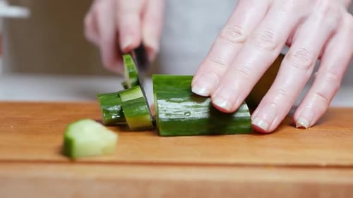 Schneiden von frischen grünen Gurken auf einem Holzbrett in der Küche