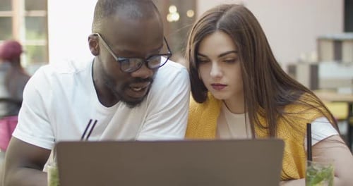 Man and Woman Working on Laptop at Cafe