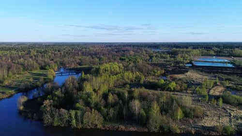 Flying above spring forest and lakes under blue sky