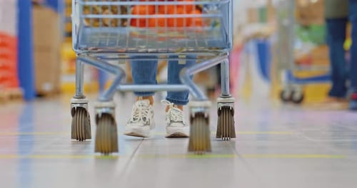Woman is Carrying a Grocery Cart in a Supermarket