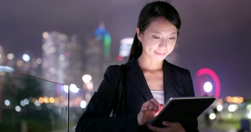 Woman Uses Tablet in City at Night