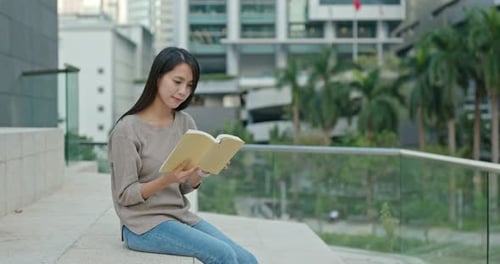 Young Woman Reads a Book in the City