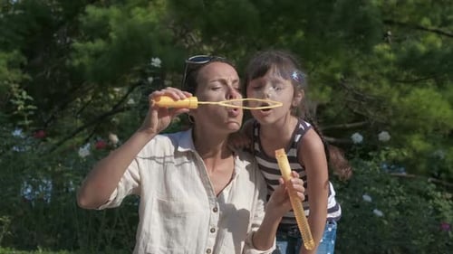 Mother and Daughter Blowing Bubbles in the Park