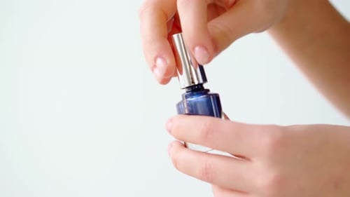 Hands Opening Dark Blue Nail Polish Bottle