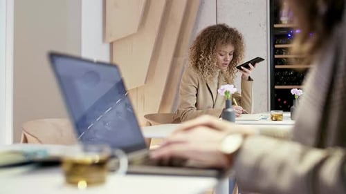 Pair of Businesswomen Using Devices in Office
