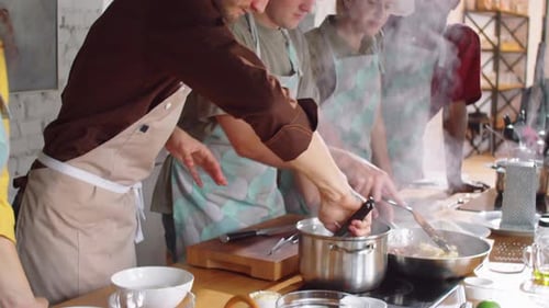Chef Cooking Pasta with Assistance of Students during Culinary Class