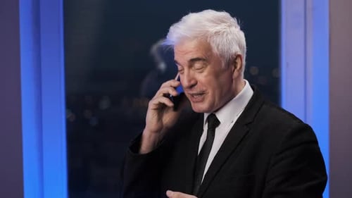 Senior Businessman Talking on Phone in Office at Night