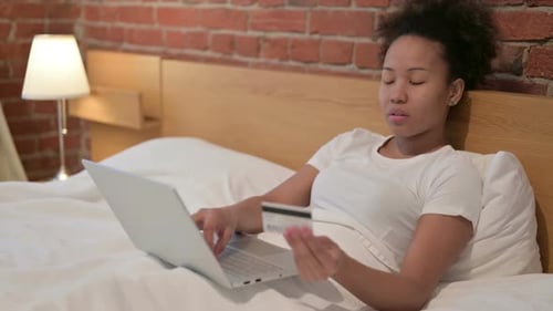 Woman with Laptop and Credit Card in Bed