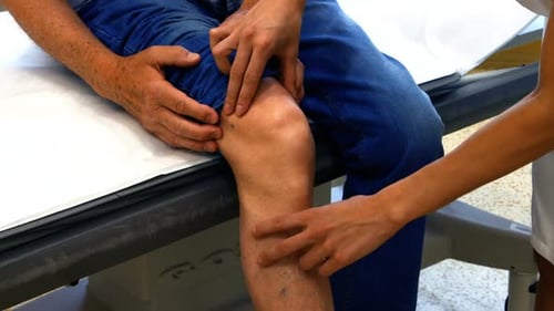 Ärztin untersucht das Knie des Patienten