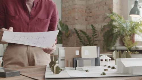 Architect Reviewing Plans Beside Modern House Model