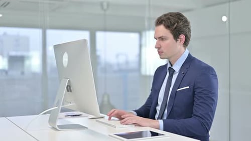 Focused Young Businessman Working on Desk Top in Office