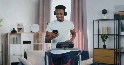 Man Exercising on Treadmill with Phone and Headphones