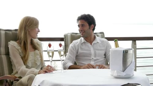 Couple Toasting with Champagne on Balcony Overlooking Ocean