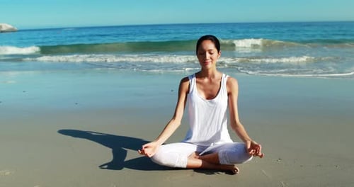 Woman performing yoga at beach