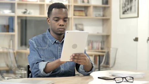 Young Adult Using Tablet Indoors at Desk