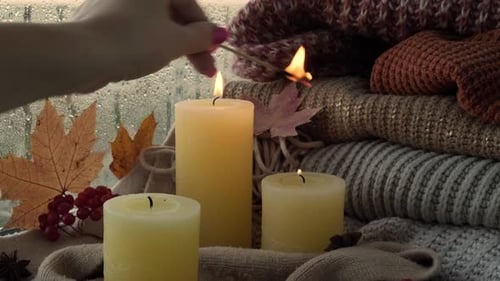 Woman Lighting Candles by Rainy Window