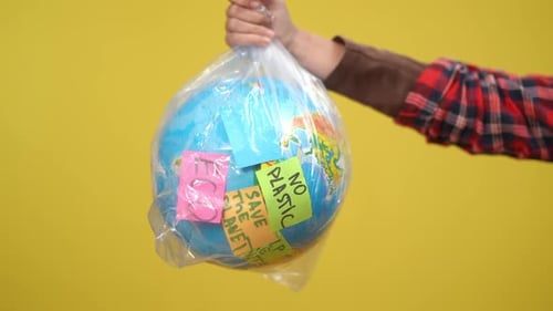 Hand Holds Globe in Plastic Bag